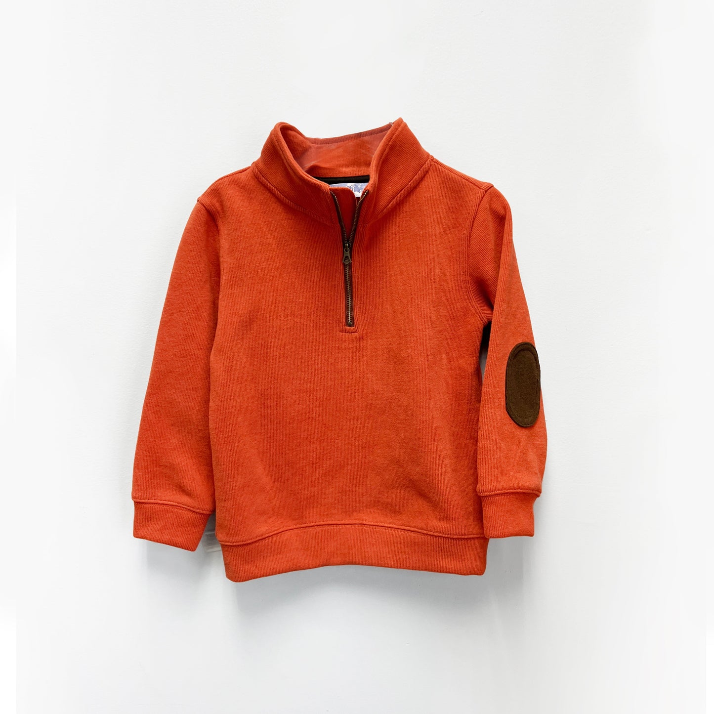
                  
                    Burnt orange boys’ quarter-zip sweater with stand-up collar and dark brown elbow patch, laid flat

                  
                